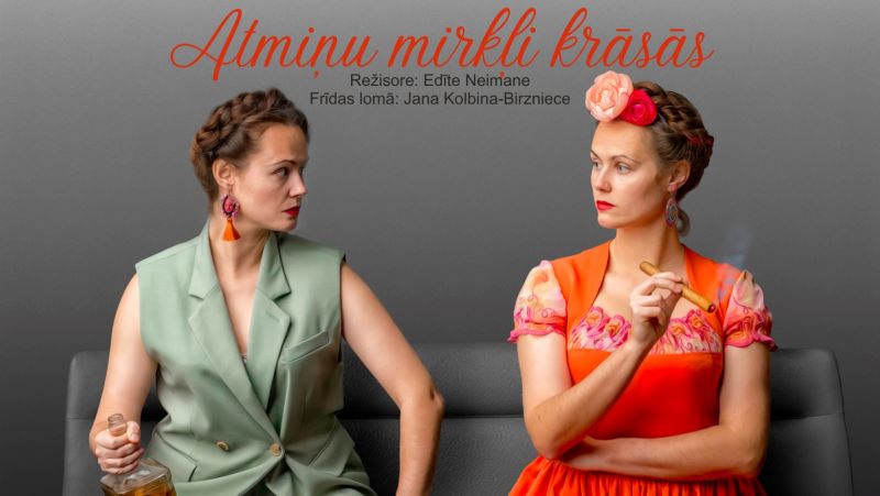 Divas sievietes, viena zaļā žaketē ar pudeli, otra oranžā kleitā ar ziediem matos un cigāru, sēžot skatās viena uz otru. Virs tām teksts: Atmiņu mirkļi krāsās. Režisore: Edīte Neimane. Frīdas lomā: Jana Kolbina-Birzniece.